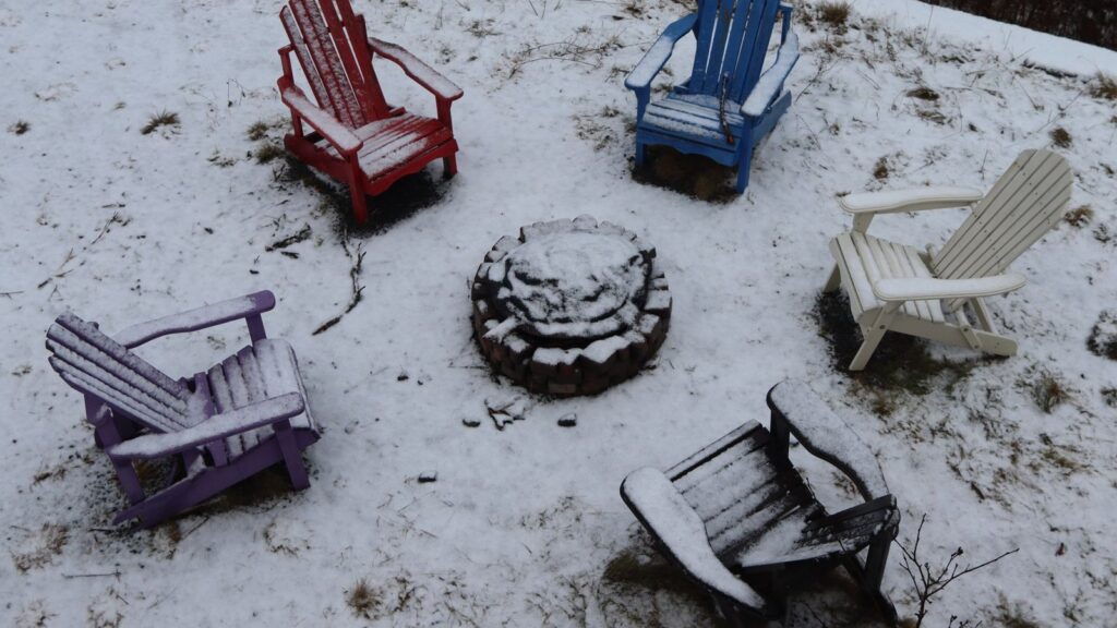 Snowy backyard with chairs around a fire pit