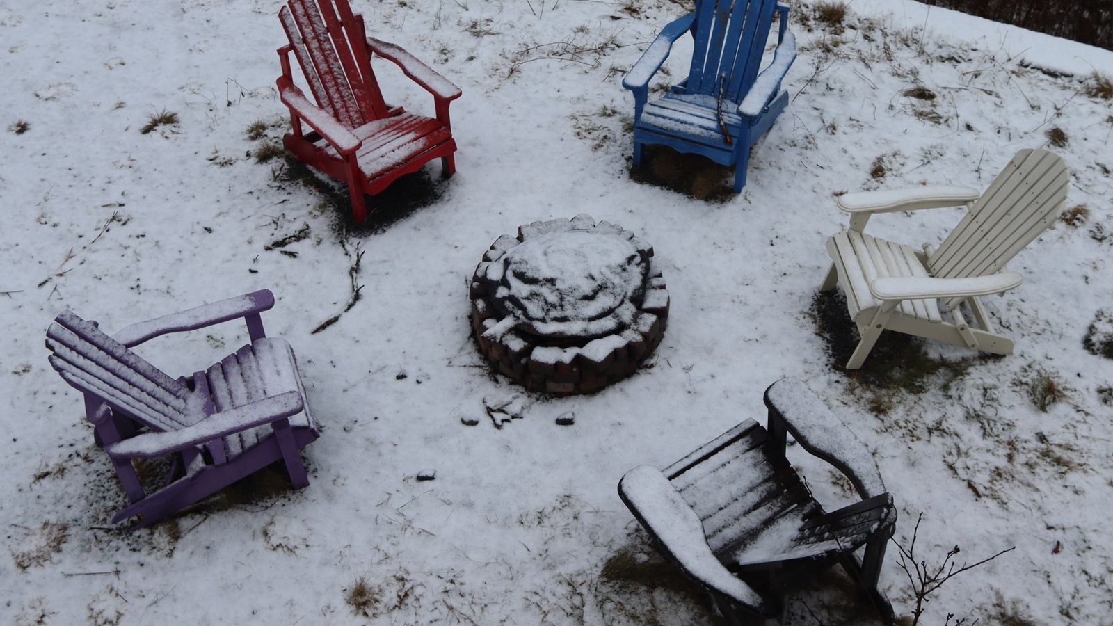 Snowy backyard with chairs around a fire pit